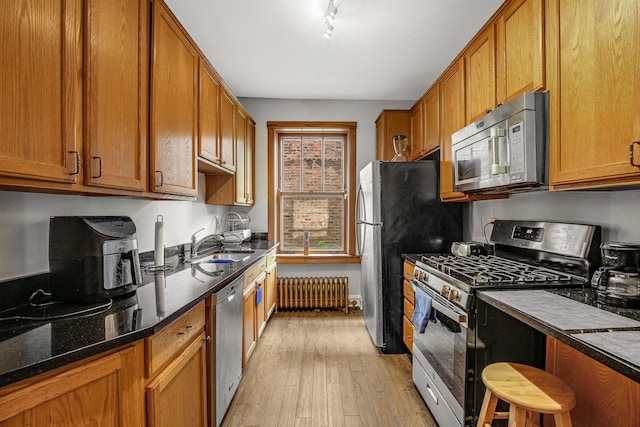 kitchen with brown cabinets, a sink, stainless steel appliances, radiator, and light wood finished floors