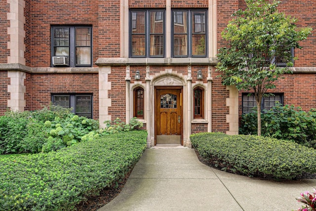 view of exterior entry featuring cooling unit and brick siding