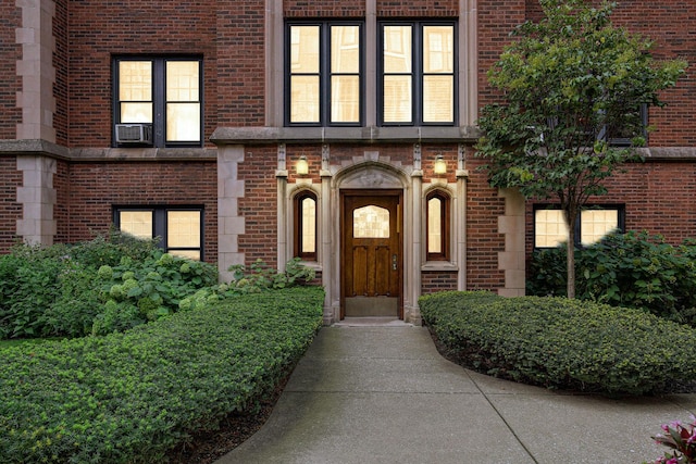 view of exterior entry featuring cooling unit and brick siding