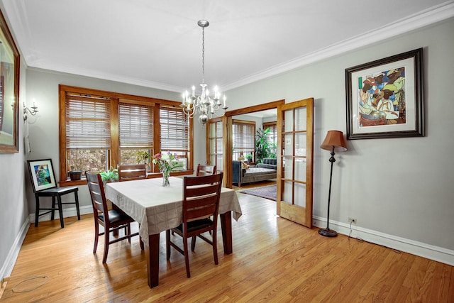 dining room featuring crown molding, baseboards, light wood-type flooring, and an inviting chandelier