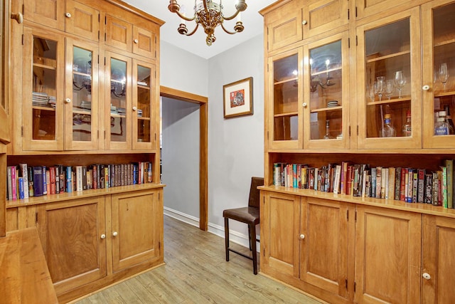 interior space with a notable chandelier, light wood-style floors, and baseboards