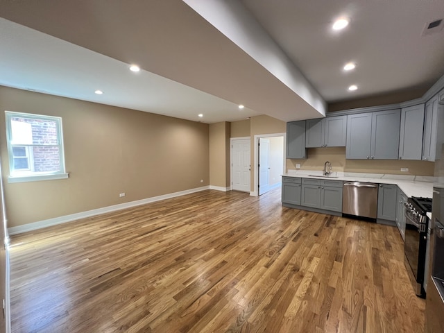 kitchen featuring gray cabinetry, stainless steel appliances, light hardwood / wood-style floors, and sink