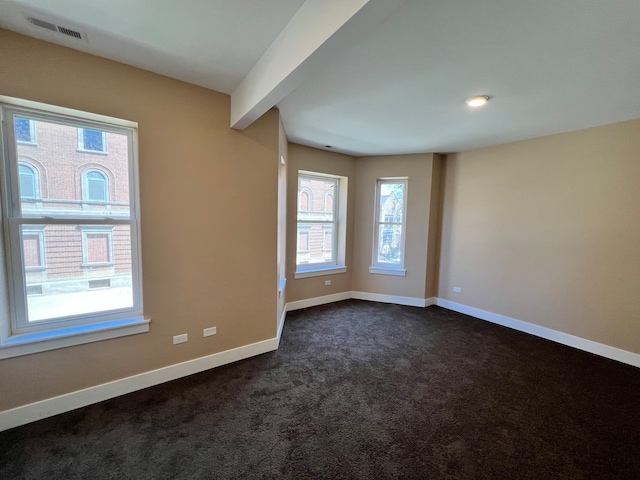 carpeted empty room featuring beam ceiling