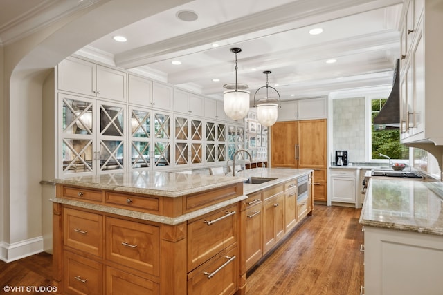 kitchen featuring white cabinetry, wall chimney exhaust hood, a center island, light hardwood / wood-style flooring, and sink