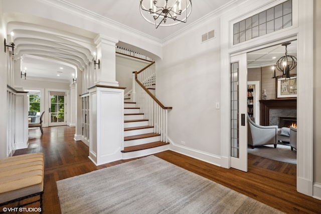 foyer with a notable chandelier, ornamental molding, dark hardwood / wood-style floors, and a fireplace