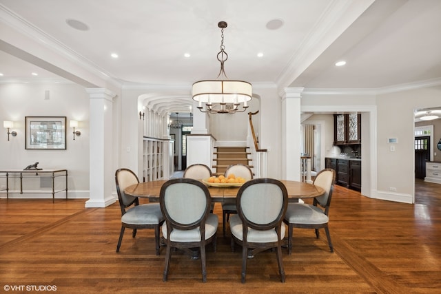 dining room featuring ornamental molding, a chandelier, ornate columns, and dark hardwood / wood-style floors