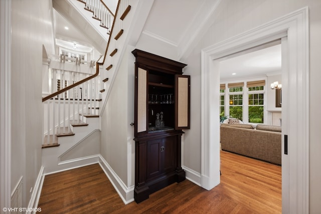 staircase with a notable chandelier, crown molding, and hardwood / wood-style flooring