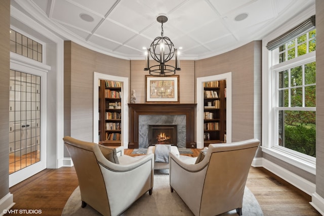 living room featuring coffered ceiling, hardwood / wood-style flooring, a fireplace, and a notable chandelier