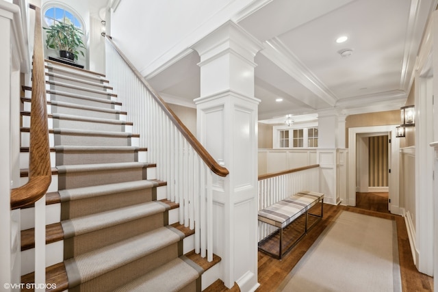 stairway with crown molding, hardwood / wood-style floors, and ornate columns