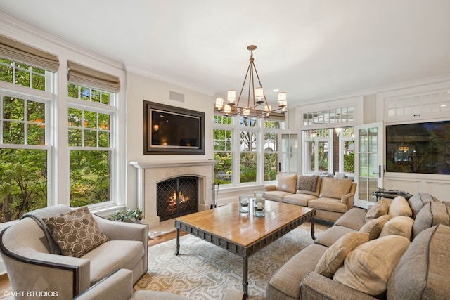 living room featuring an inviting chandelier, light wood-type flooring, a healthy amount of sunlight, and crown molding