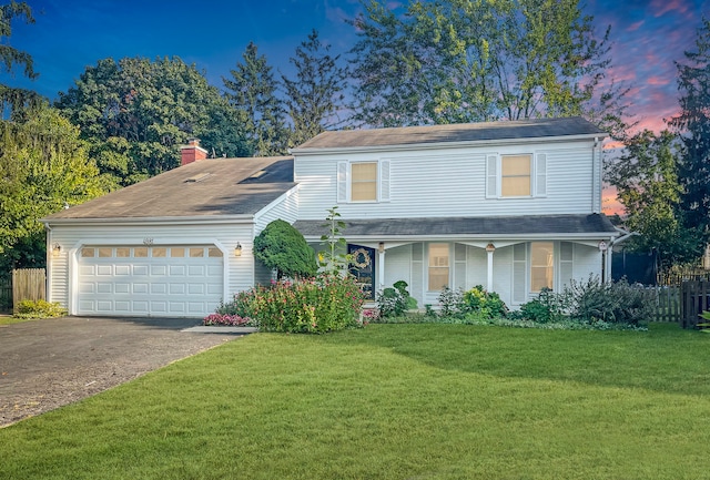 front of property featuring a lawn, a garage, and covered porch