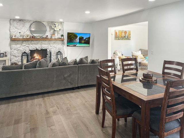 dining area with light hardwood / wood-style flooring and a stone fireplace