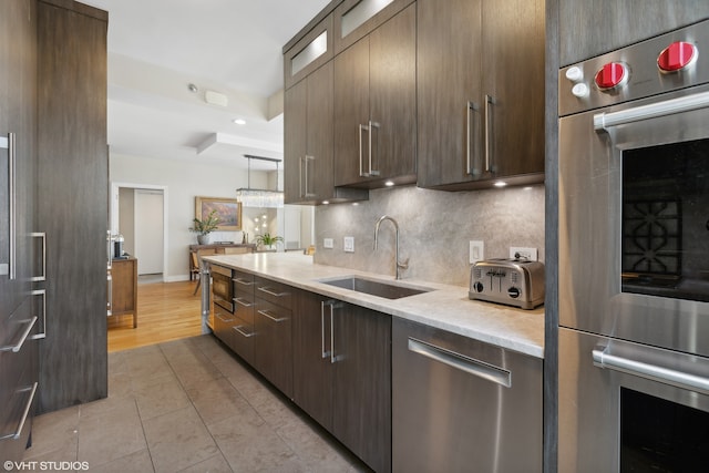 kitchen with light stone countertops, a tray ceiling, light hardwood / wood-style floors, stainless steel appliances, and sink