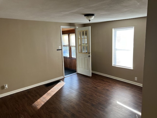 spare room with a textured ceiling and dark wood-type flooring