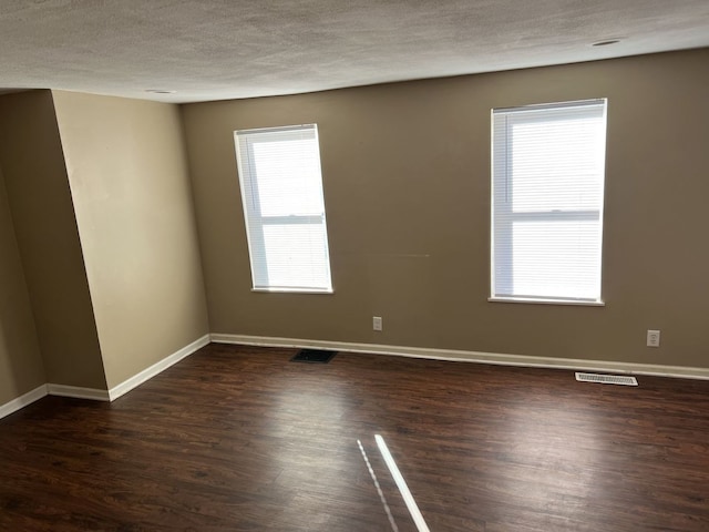 empty room with dark hardwood / wood-style floors and a textured ceiling