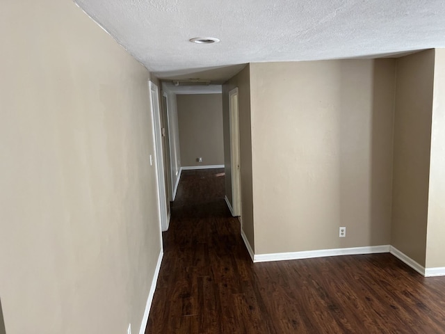 hallway with a textured ceiling and dark hardwood / wood-style flooring