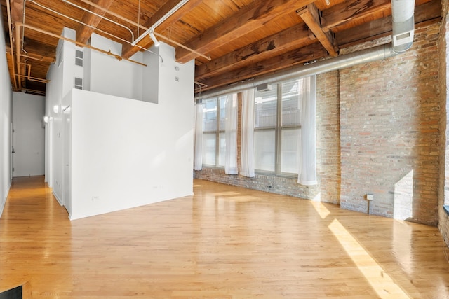 unfurnished room featuring light hardwood / wood-style floors, wooden ceiling, and brick wall