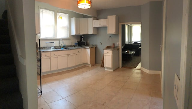 kitchen with white cabinets, a wealth of natural light, light tile patterned floors, and sink