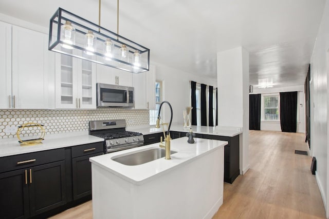 kitchen with a sink, stainless steel appliances, light wood-style floors, and light countertops