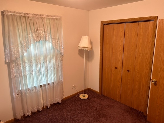 unfurnished bedroom featuring dark carpet and a closet