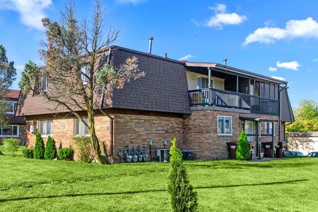 rear view of house with a balcony and a yard