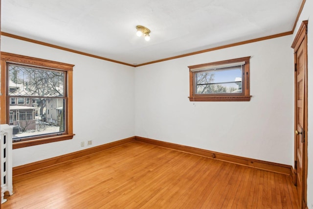 empty room with ornamental molding and light wood-type flooring