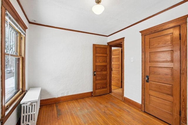 unfurnished room with light wood-type flooring, radiator, and ornamental molding