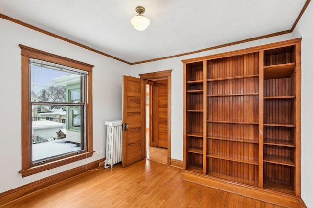 unfurnished bedroom with light hardwood / wood-style floors, radiator heating unit, and ornamental molding