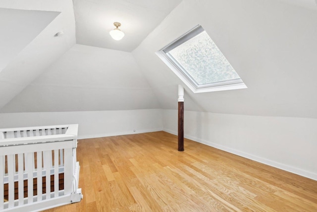 additional living space with hardwood / wood-style floors and lofted ceiling with skylight