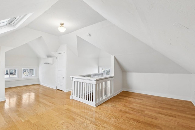 bonus room with light hardwood / wood-style flooring, a wall unit AC, and vaulted ceiling