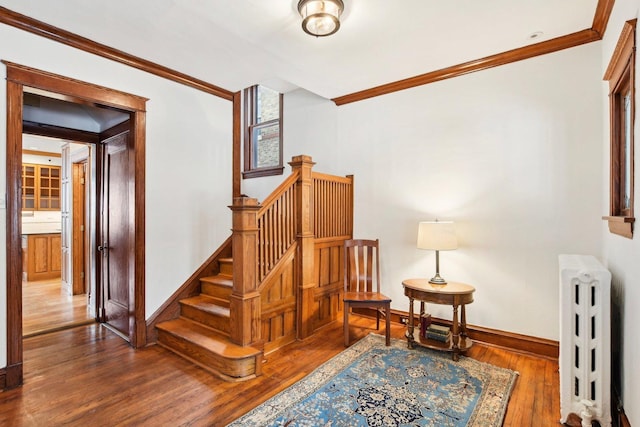 stairway with wood-type flooring, radiator heating unit, and ornamental molding