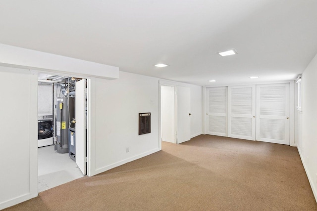 basement featuring light carpet, washer / clothes dryer, and water heater