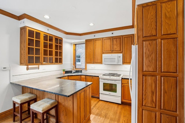 kitchen featuring kitchen peninsula, decorative backsplash, a breakfast bar, white appliances, and crown molding