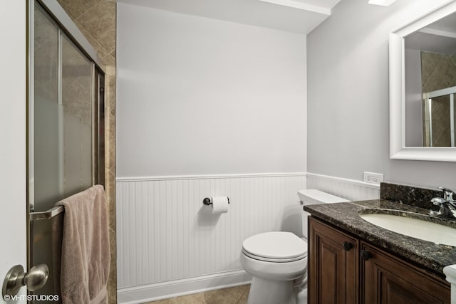 bathroom featuring vanity, toilet, a shower with shower door, and tile patterned flooring