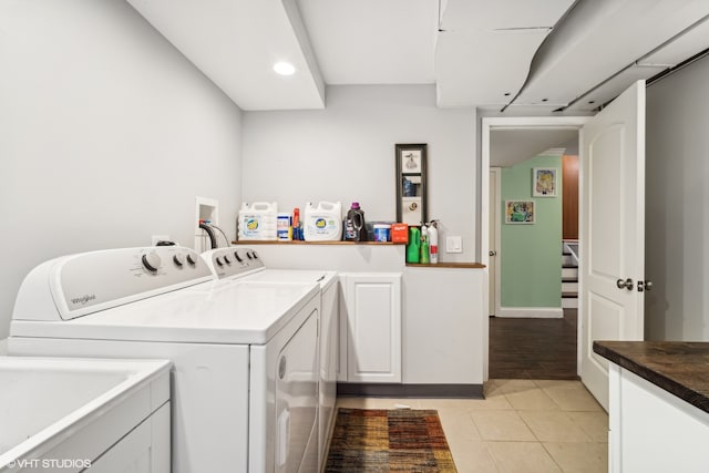 washroom with light wood-type flooring, cabinets, and washer and clothes dryer