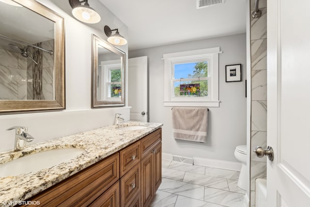 bathroom with toilet, a tile shower, and vanity