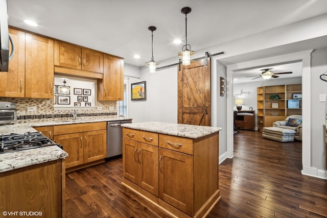 kitchen featuring dark hardwood / wood-style floors, stainless steel dishwasher, hanging light fixtures, a barn door, and ceiling fan