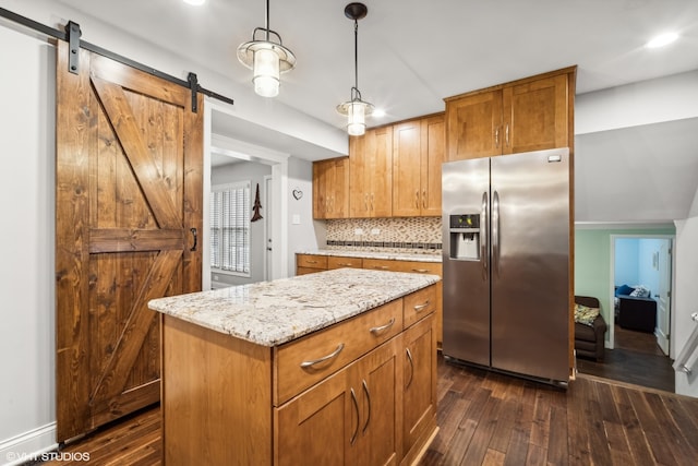 kitchen featuring a kitchen island, dark hardwood / wood-style floors, stainless steel fridge with ice dispenser, hanging light fixtures, and a barn door