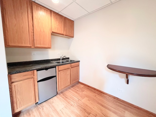 kitchen with stainless steel dishwasher, a drop ceiling, sink, and light hardwood / wood-style flooring