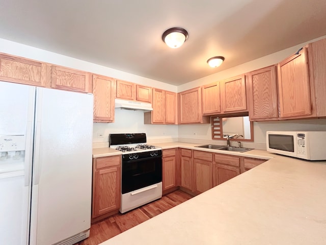 kitchen with white appliances, light brown cabinetry, sink, and light wood-type flooring