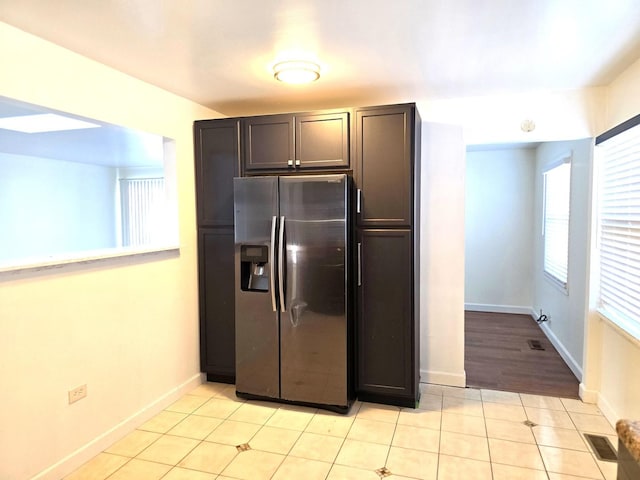 kitchen featuring stainless steel refrigerator with ice dispenser, dark brown cabinetry, and light tile patterned floors