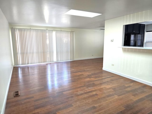 spare room featuring dark hardwood / wood-style floors and a skylight