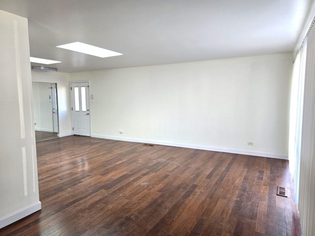 empty room featuring a skylight and dark wood-type flooring