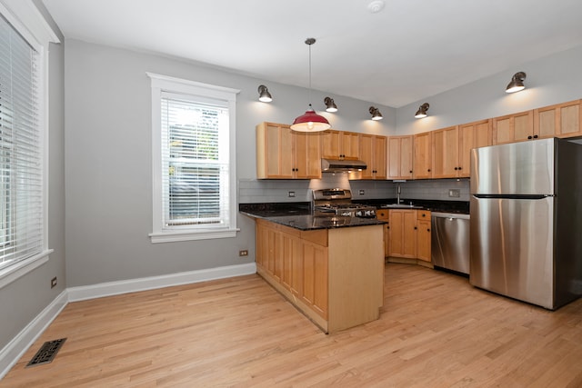 kitchen with decorative light fixtures, appliances with stainless steel finishes, kitchen peninsula, and light hardwood / wood-style flooring