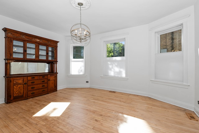 unfurnished dining area with light hardwood / wood-style floors and a chandelier