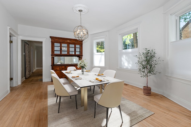 dining room with plenty of natural light, a notable chandelier, and light wood-type flooring