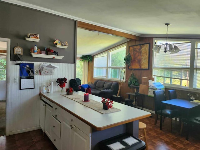 kitchen featuring pendant lighting, kitchen peninsula, ornamental molding, dark parquet floors, and white cabinets