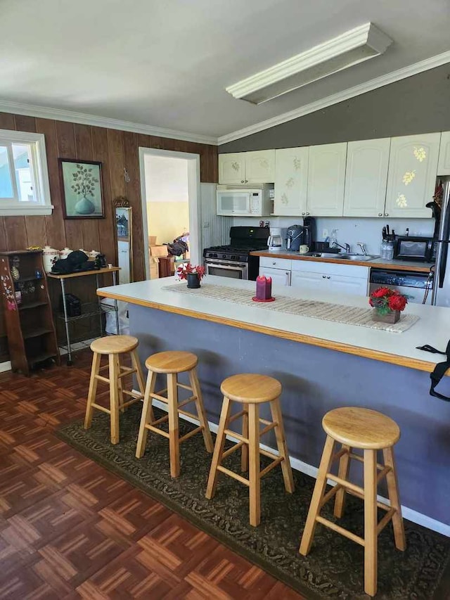 kitchen featuring ornamental molding, white cabinetry, stainless steel appliances, and a breakfast bar