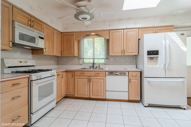 kitchen with white appliances, a skylight, light tile patterned floors, sink, and ceiling fan