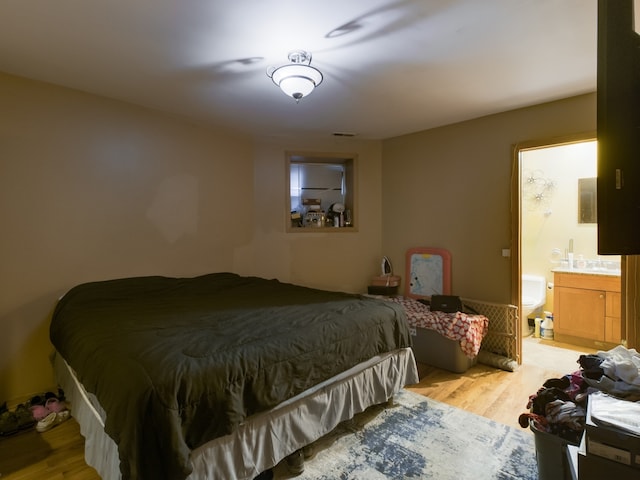 bedroom featuring ensuite bath and light hardwood / wood-style floors